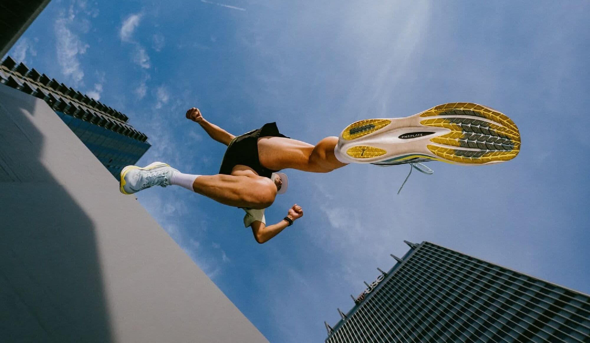 Atleta en pleno salto visto desde abajo, entre edificios